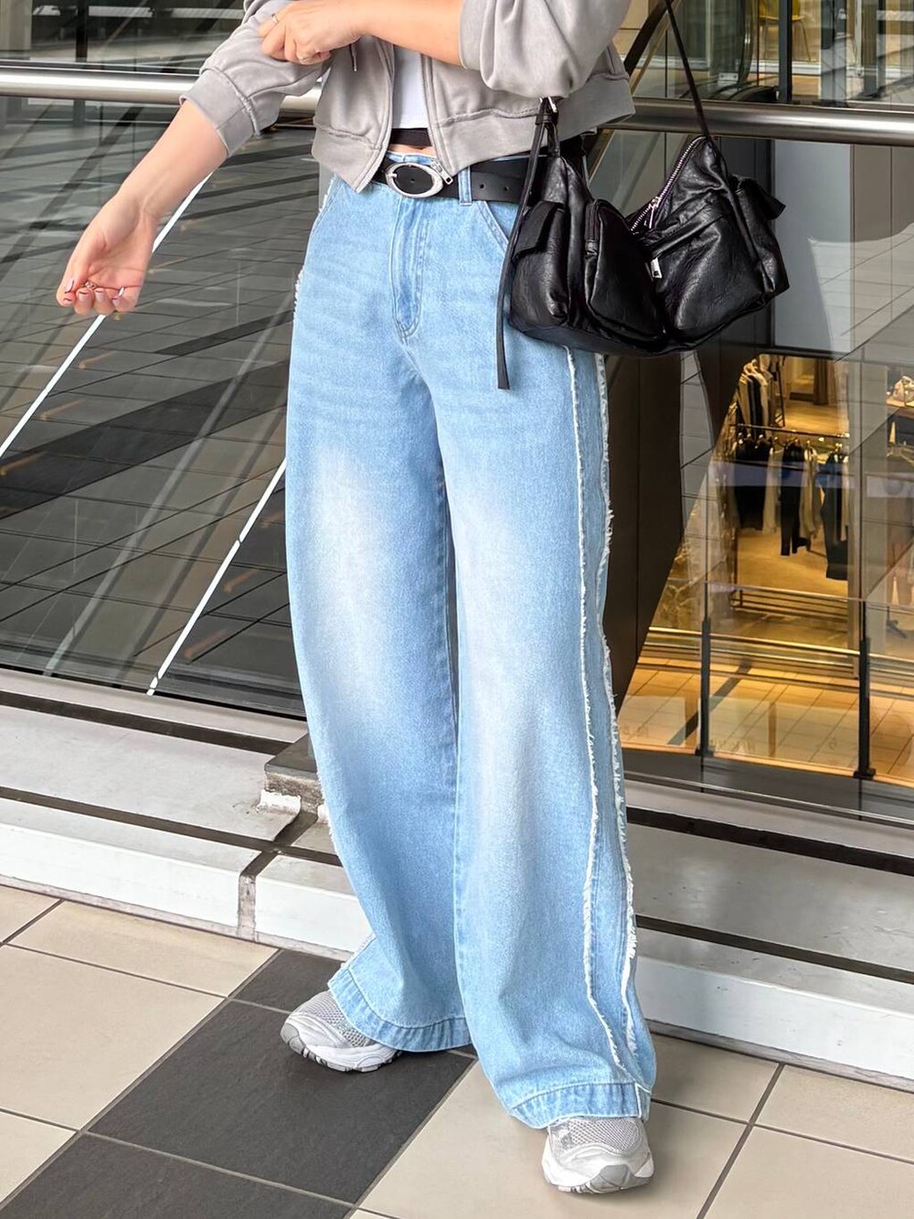 ブラック系のショルダーバッグ、ブルー系のデニムパンツ、ホワイト系のハットを着用したレディースの春コーディネートの5枚目の写真