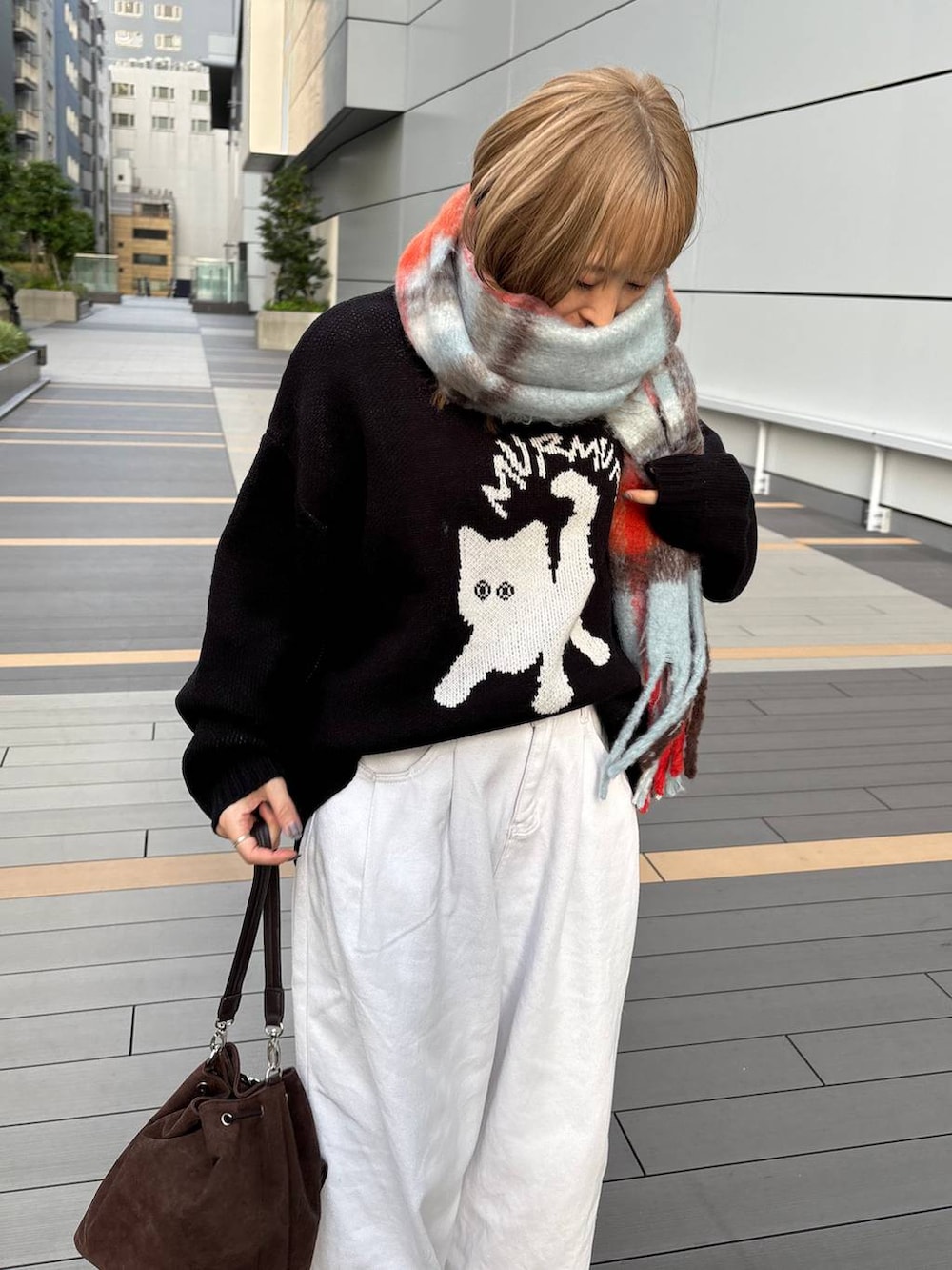 ブラウン系のショルダーバッグ、ブラック系のニット/セーター、ブルー系のマフラーを着用したレディースの秋コーディネートの3枚目の写真