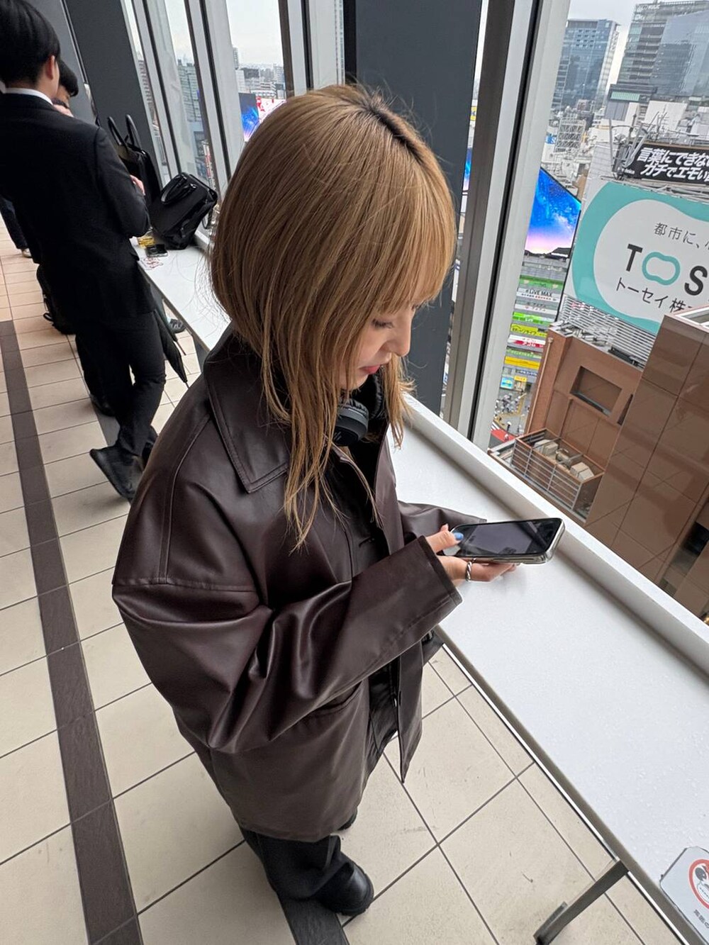 ブラウン系のステンカラーコート、ブラック系のボストンバッグを着用したレディースの秋コーディネートの5枚目の写真