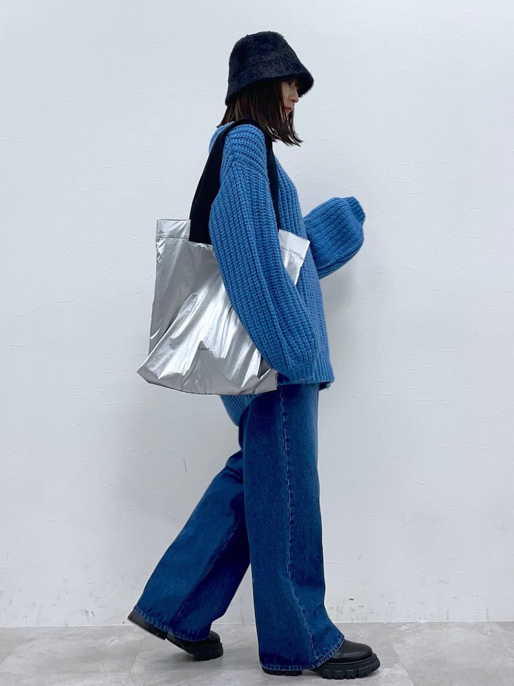 ブラック系のブーツ、ブルー系のデニムパンツ、シルバー系のトートバッグを着用したレディースの秋コーディネートの4枚目の写真