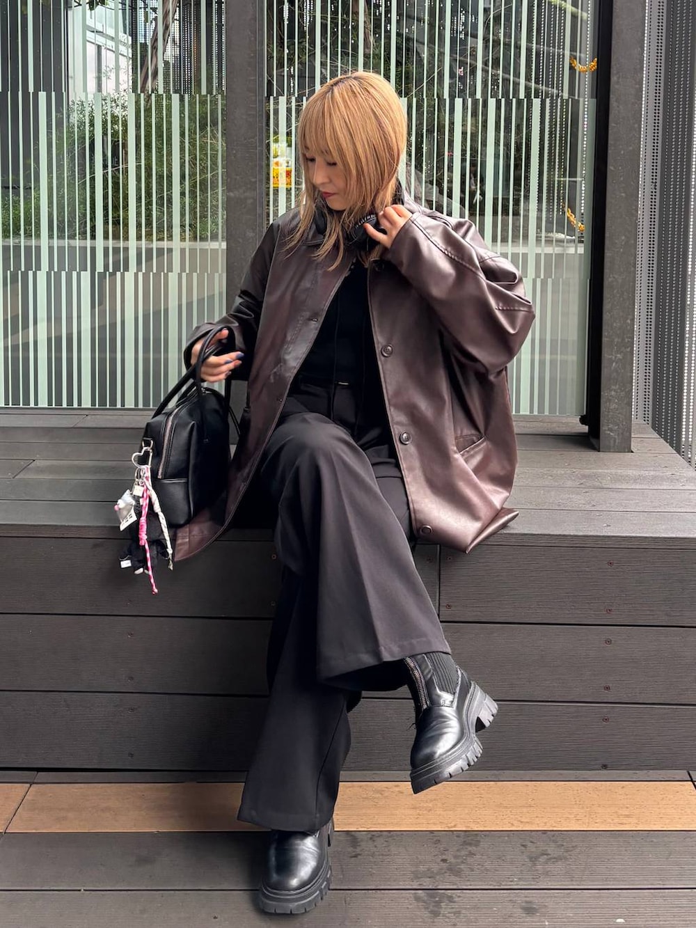 ブラウン系のステンカラーコート、ブラック系のボストンバッグを着用したレディースの秋コーディネートの2枚目の写真