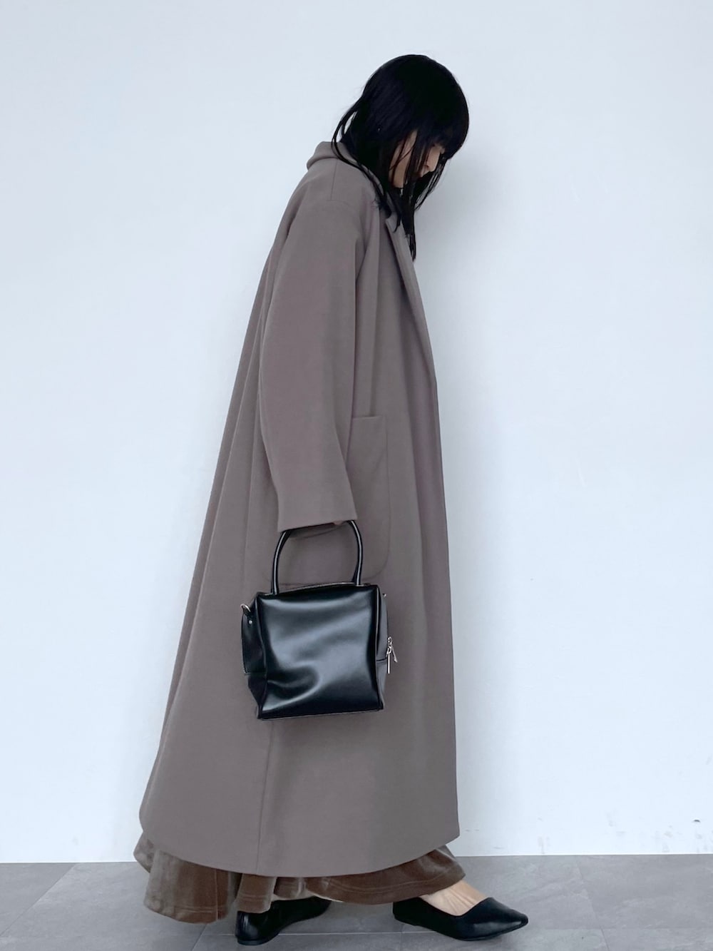 ベージュ系のチェスターコート、ブラック系のショルダーバッグ、ブラウン系のスカートを着用したレディースの冬コーディネートの2枚目の写真