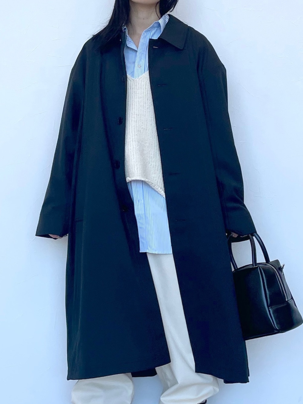 ブラック系のステンカラーコート、ベージュ系のニット/セーター、ブルー系のシャツ/ブラウスを着用したレディースの冬コーディネートの6枚目の写真