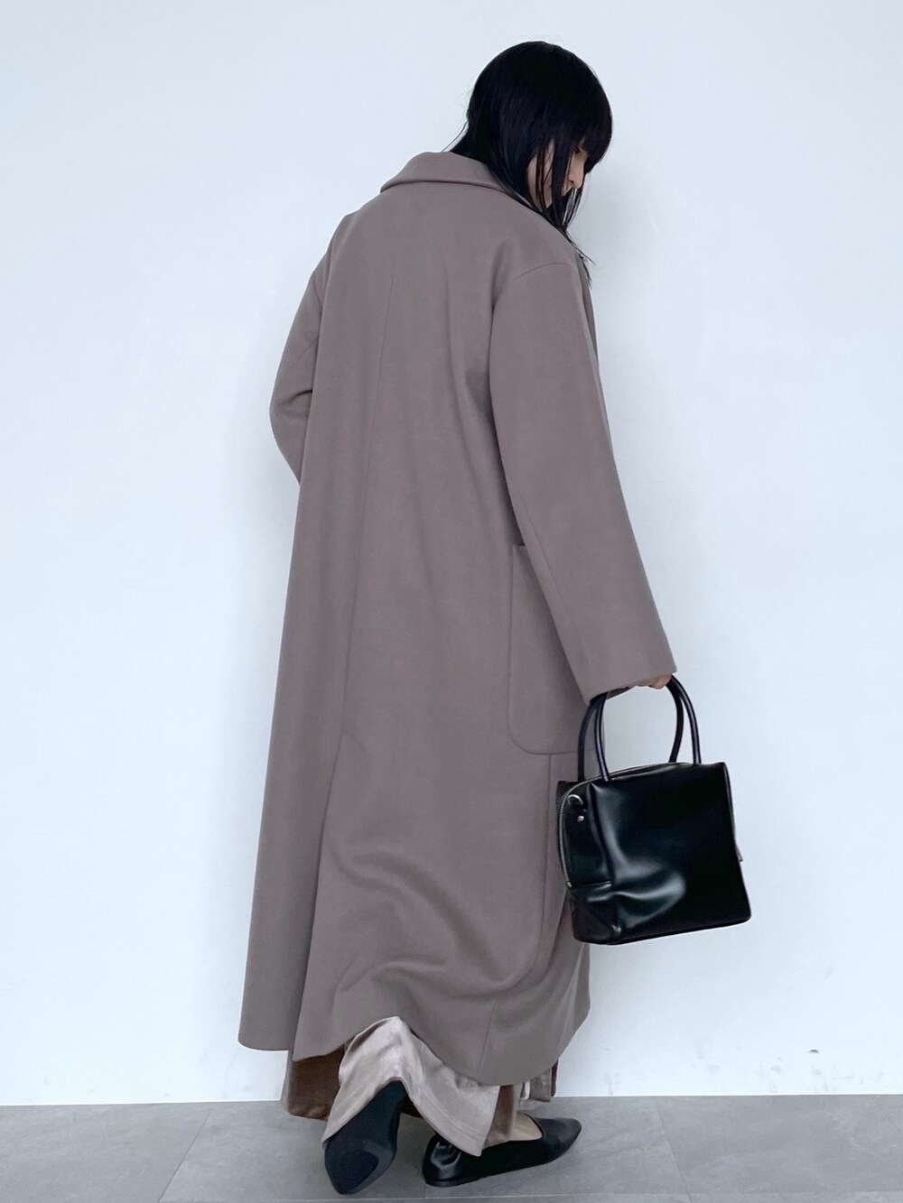 ベージュ系のチェスターコート、ブラック系のショルダーバッグ、ブラウン系のスカートを着用したレディースの冬コーディネートの3枚目の写真