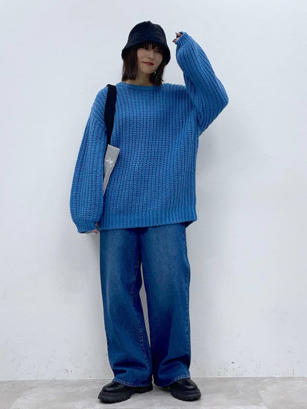 ブラック系のブーツ、ブルー系のデニムパンツ、シルバー系のトートバッグを着用したレディースの秋コーディネートの5枚目の写真