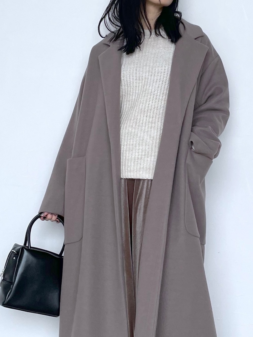 ベージュ系のチェスターコート、ブラック系のショルダーバッグ、ブラウン系のスカートを着用したレディースの冬コーディネートの5枚目の写真