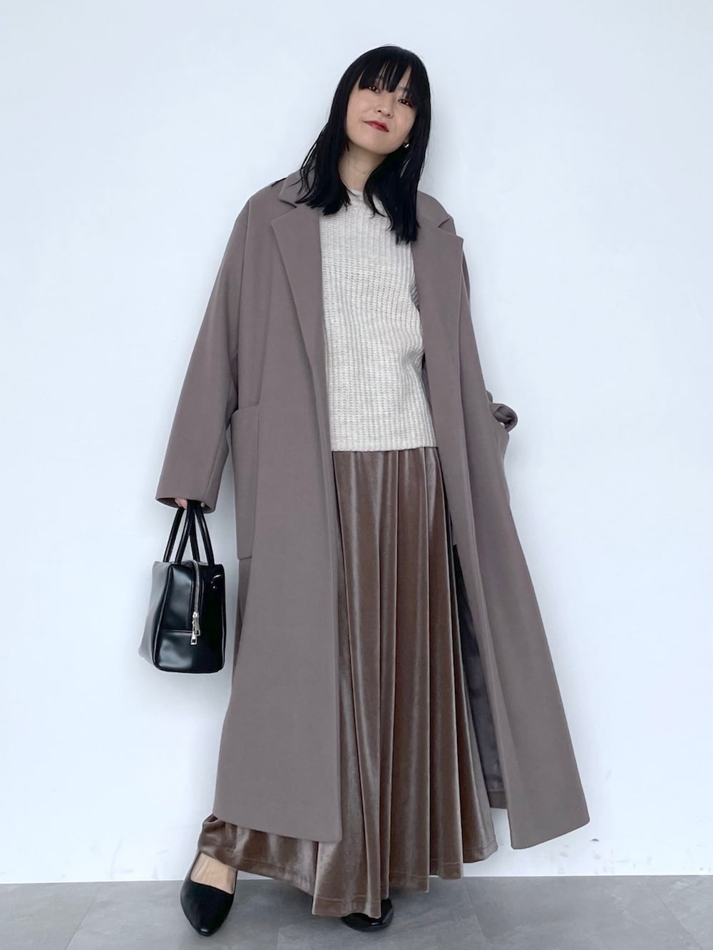ベージュ系のチェスターコート、ブラック系のショルダーバッグ、ブラウン系のスカートを着用したレディースの冬コーディネートの7枚目の写真