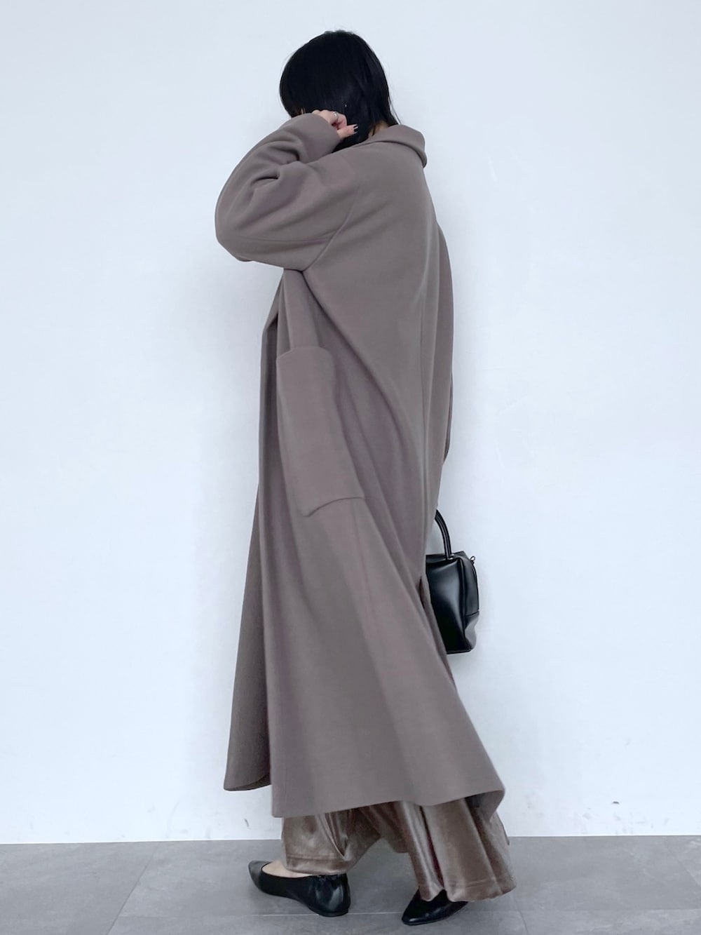 ベージュ系のチェスターコート、ブラック系のショルダーバッグ、ブラウン系のスカートを着用したレディースの冬コーディネートの4枚目の写真