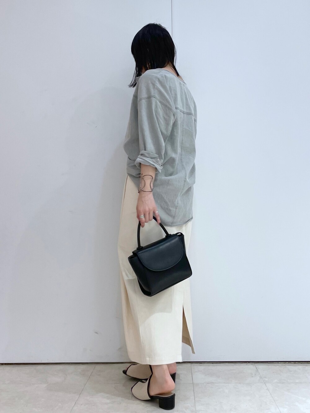 グレー系のシャツ/ブラウス、ホワイト系のスカート、ブラック系のサンダルを着用したレディースの春コーディネートの2枚目の写真