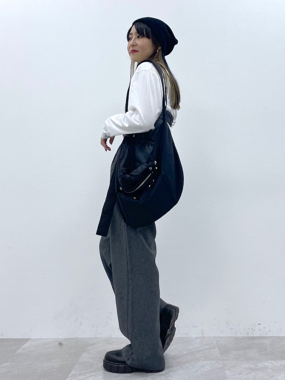 ホワイト系のトップス、ブラック系のサロペット/オーバーオール、ブラック系のブーツを着用したレディースの秋コーディネートの2枚目の写真