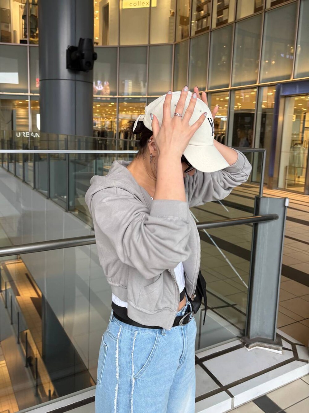 ブラック系のショルダーバッグ、ブルー系のデニムパンツ、ホワイト系のハットを着用したレディースの春コーディネートの2枚目の写真