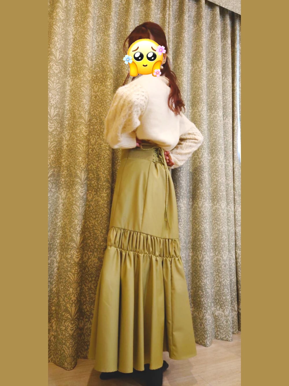 グリーン系のスカート、ホワイト系のニット/セーター、ブラック系のブーツを着用したレディースの冬コーディネートの2枚目の写真