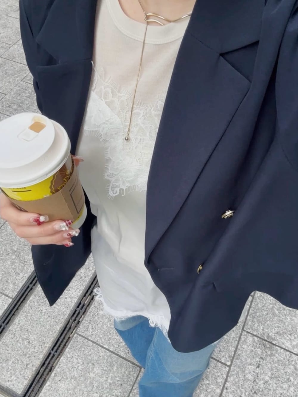 ホワイト系のチュニック、ブルー系のデニムパンツ、ブルー系のテーラードジャケットを着用したレディースの春コーディネートの2枚目の写真