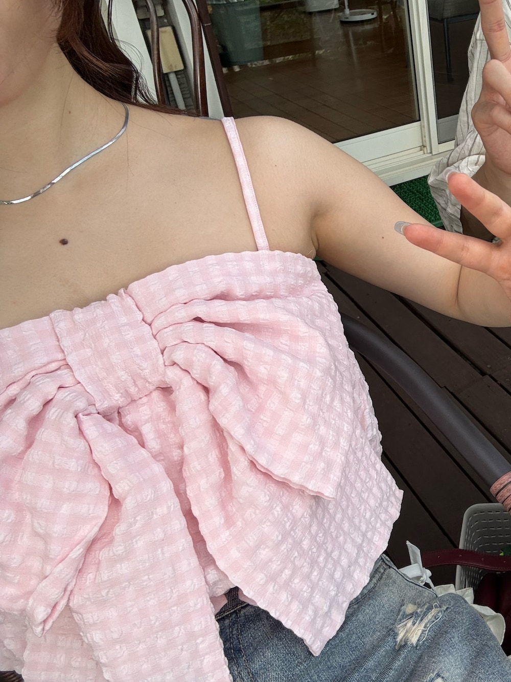 ピンク系のキャミソール、ブルー系のデニムパンツ、レッド系のショルダーバッグを着用したレディースの夏コーディネートの2枚目の写真