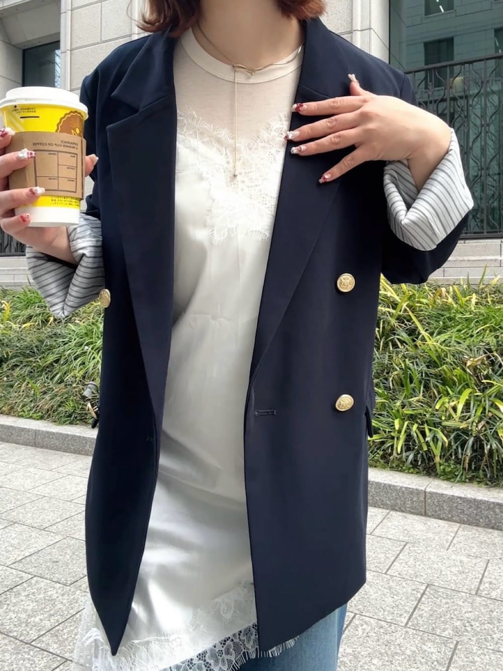 ホワイト系のチュニック、ブルー系のデニムパンツ、ブルー系のテーラードジャケットを着用したレディースの春コーディネートの3枚目の写真