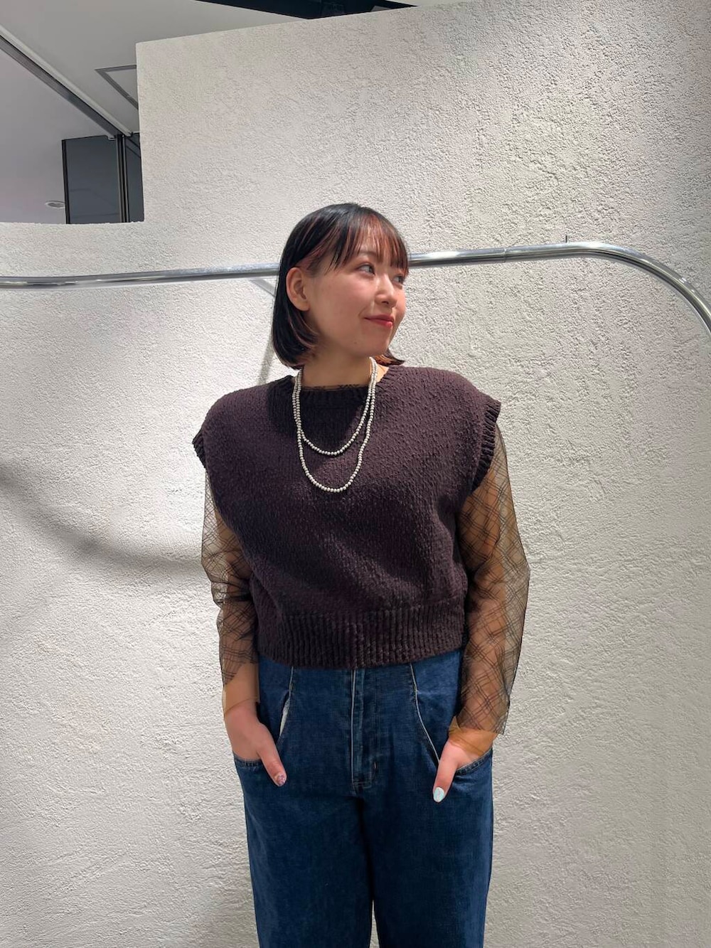 ブルー系のデニムパンツ、ブラック系のTシャツ/カットソー、ブラウン系のニット/セーターを着用したレディースの春コーディネートの5枚目の写真