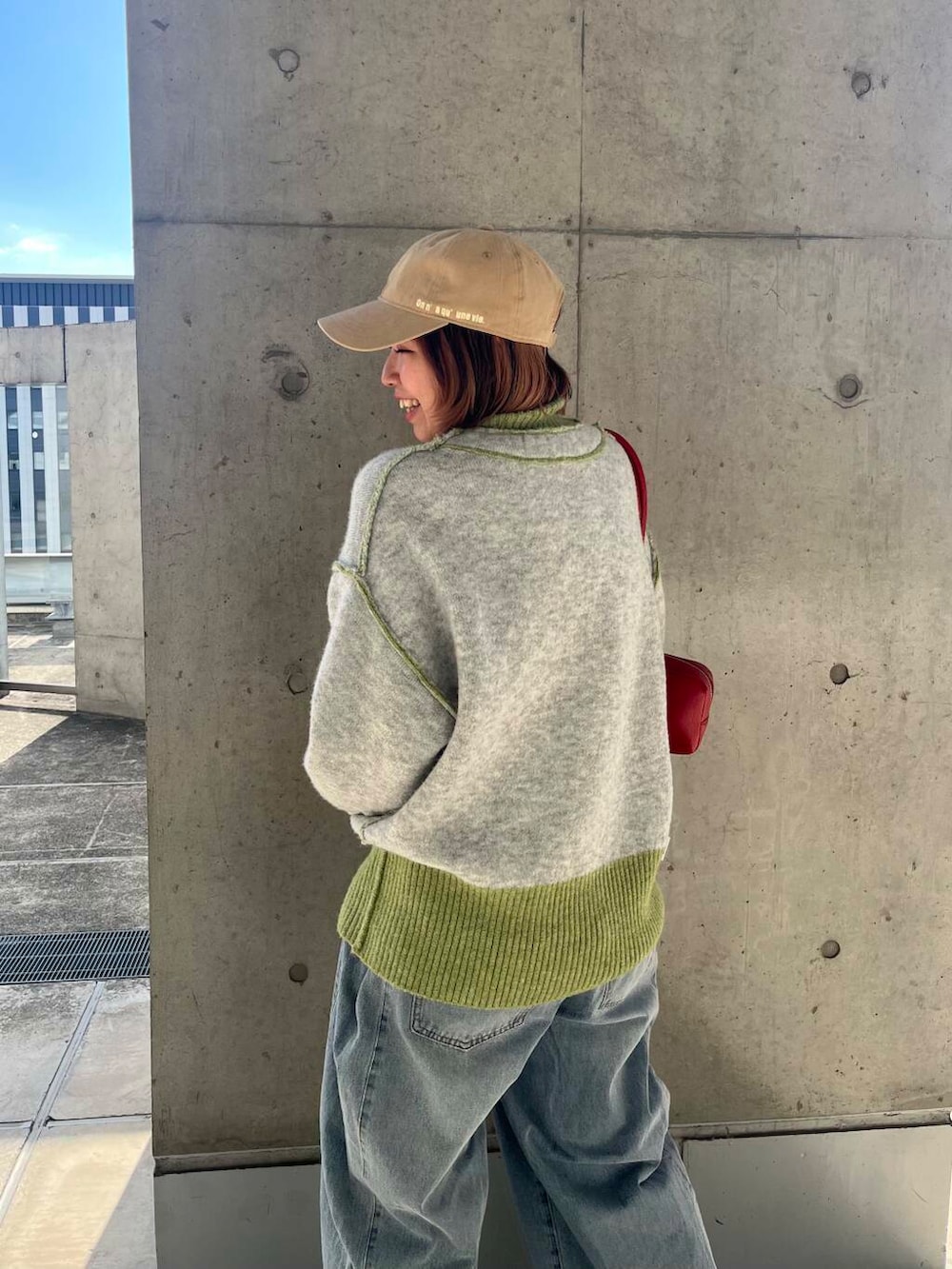 ブルー系のデニムパンツ、レッド系のショルダーバッグ、グリーン系のニット/セーターを着用したレディースの冬コーディネートの6枚目の写真