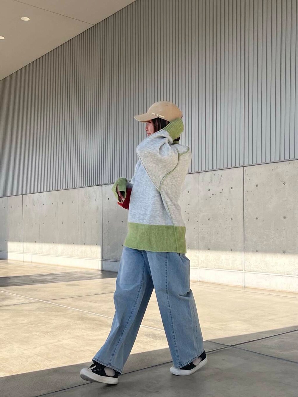 ブルー系のデニムパンツ、レッド系のショルダーバッグ、グリーン系のニット/セーターを着用したレディースの冬コーディネートの3枚目の写真