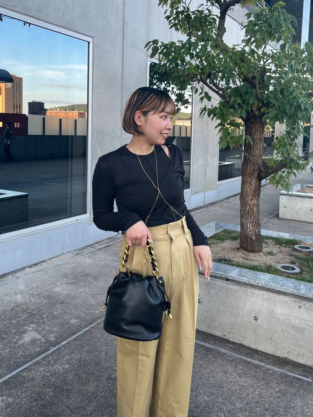 ブラック系のショルダーバッグ、ブラック系のサンダル、ベージュ系のチノパンツを着用したレディースの夏コーディネートの3枚目の写真