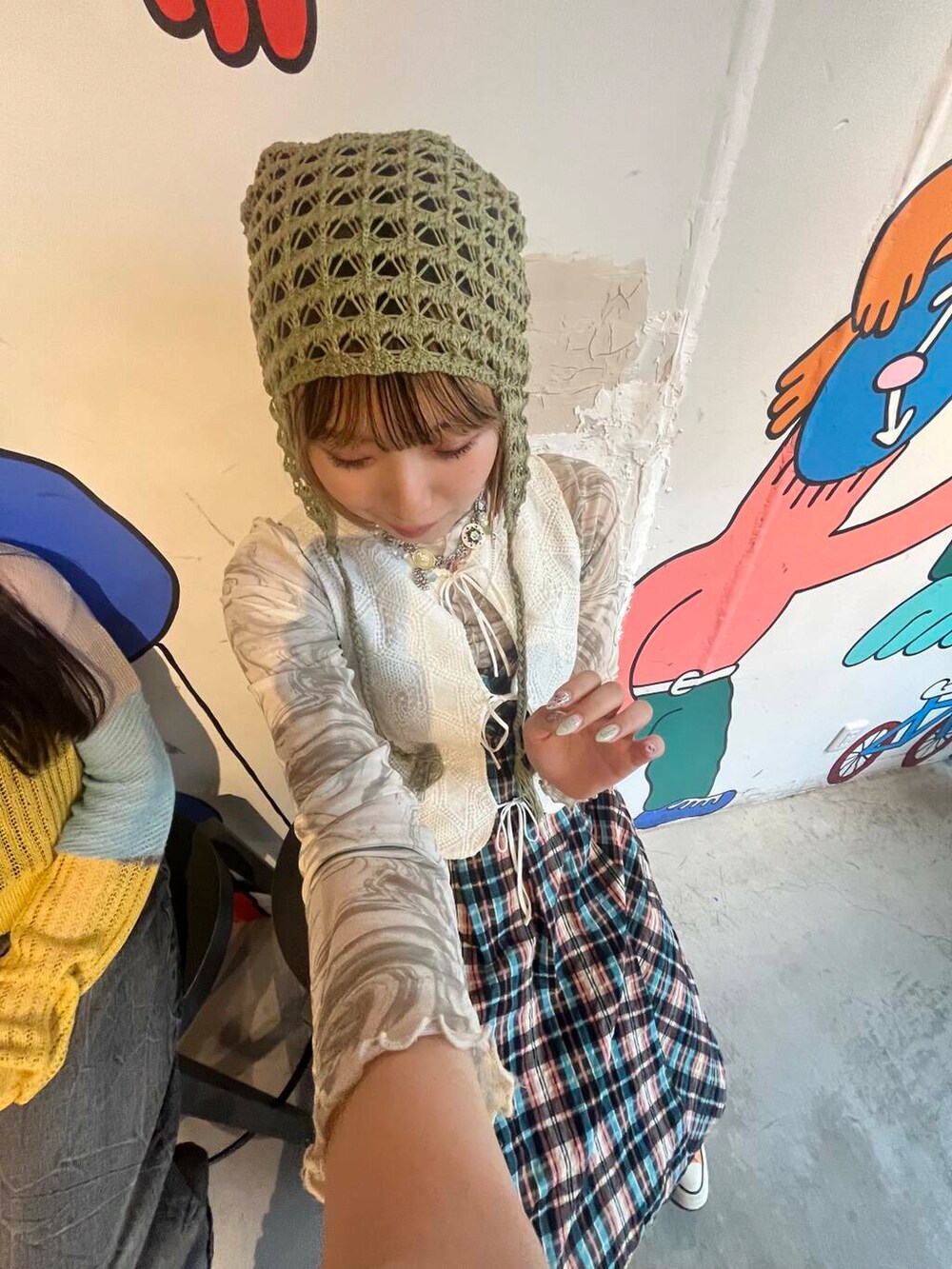 グリーン系のショルダーバッグ、ホワイト系のベスト、オレンジ系のワンピースを着用したレディースの夏コーディネートの3枚目の写真