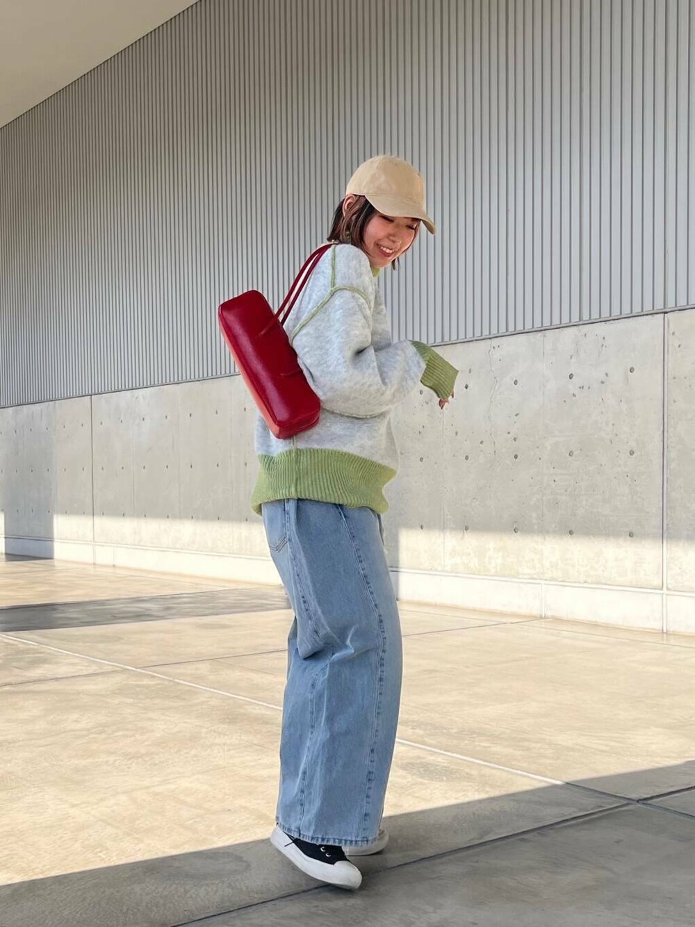 ブルー系のデニムパンツ、レッド系のショルダーバッグ、グリーン系のニット/セーターを着用したレディースの冬コーディネートの2枚目の写真