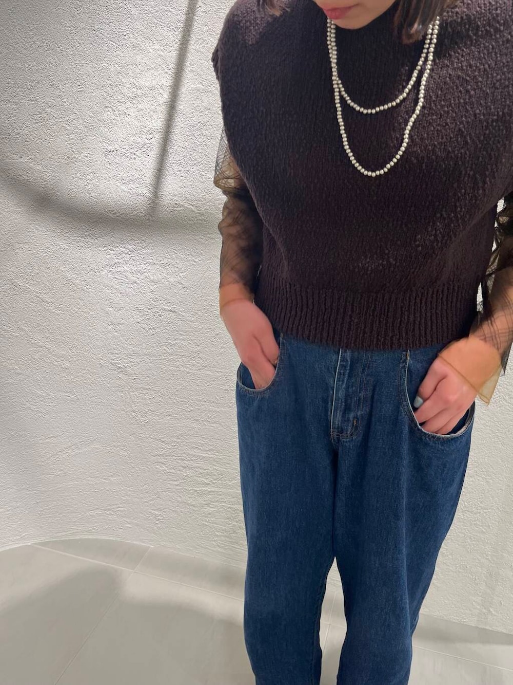 ブルー系のデニムパンツ、ブラック系のTシャツ/カットソー、ブラウン系のニット/セーターを着用したレディースの春コーディネートの8枚目の写真