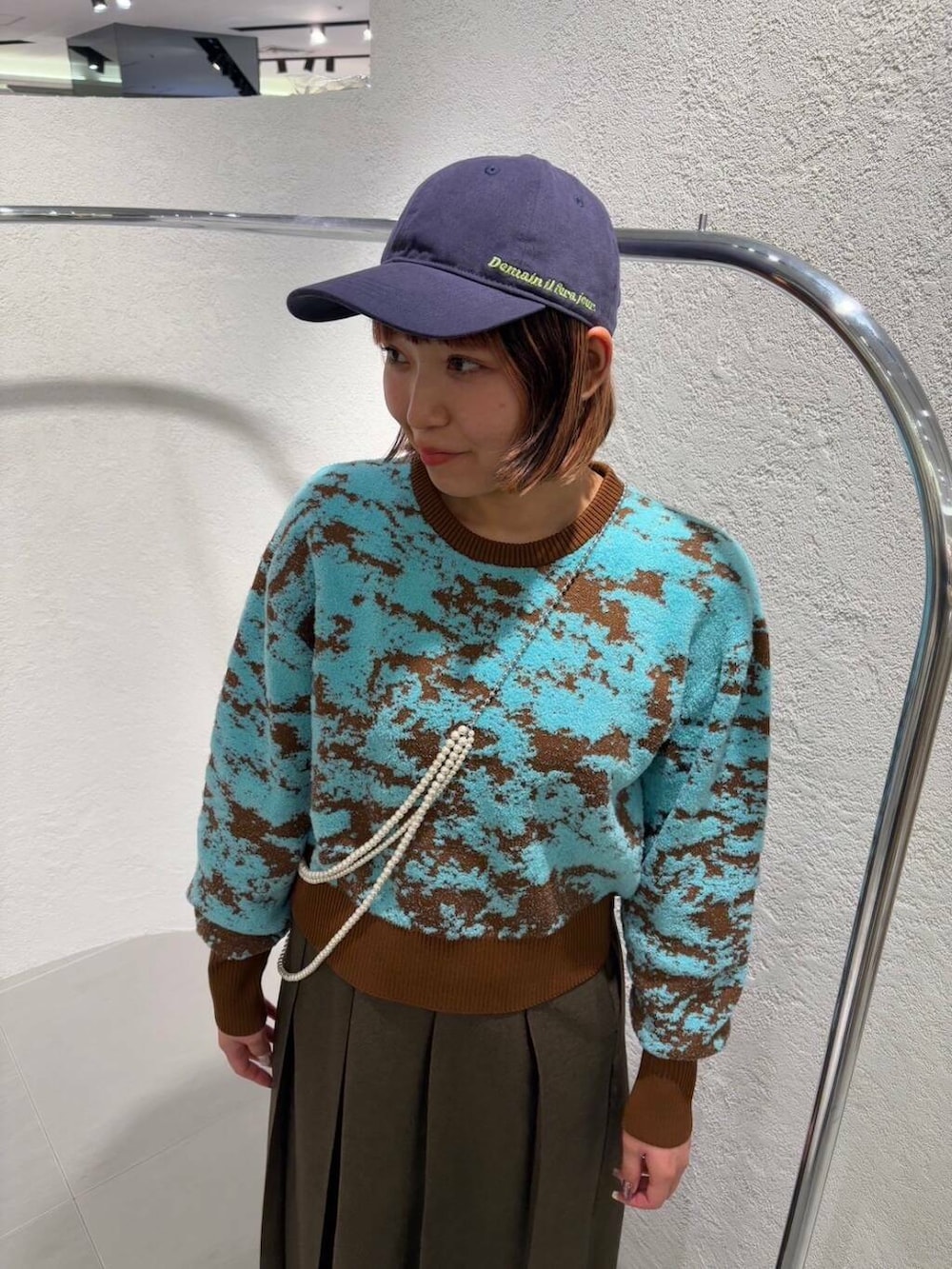 ブラウン系のニット/セーター、ブラウン系のワンピース、ブルー系のキャップを着用したレディースの冬コーディネートの4枚目の写真