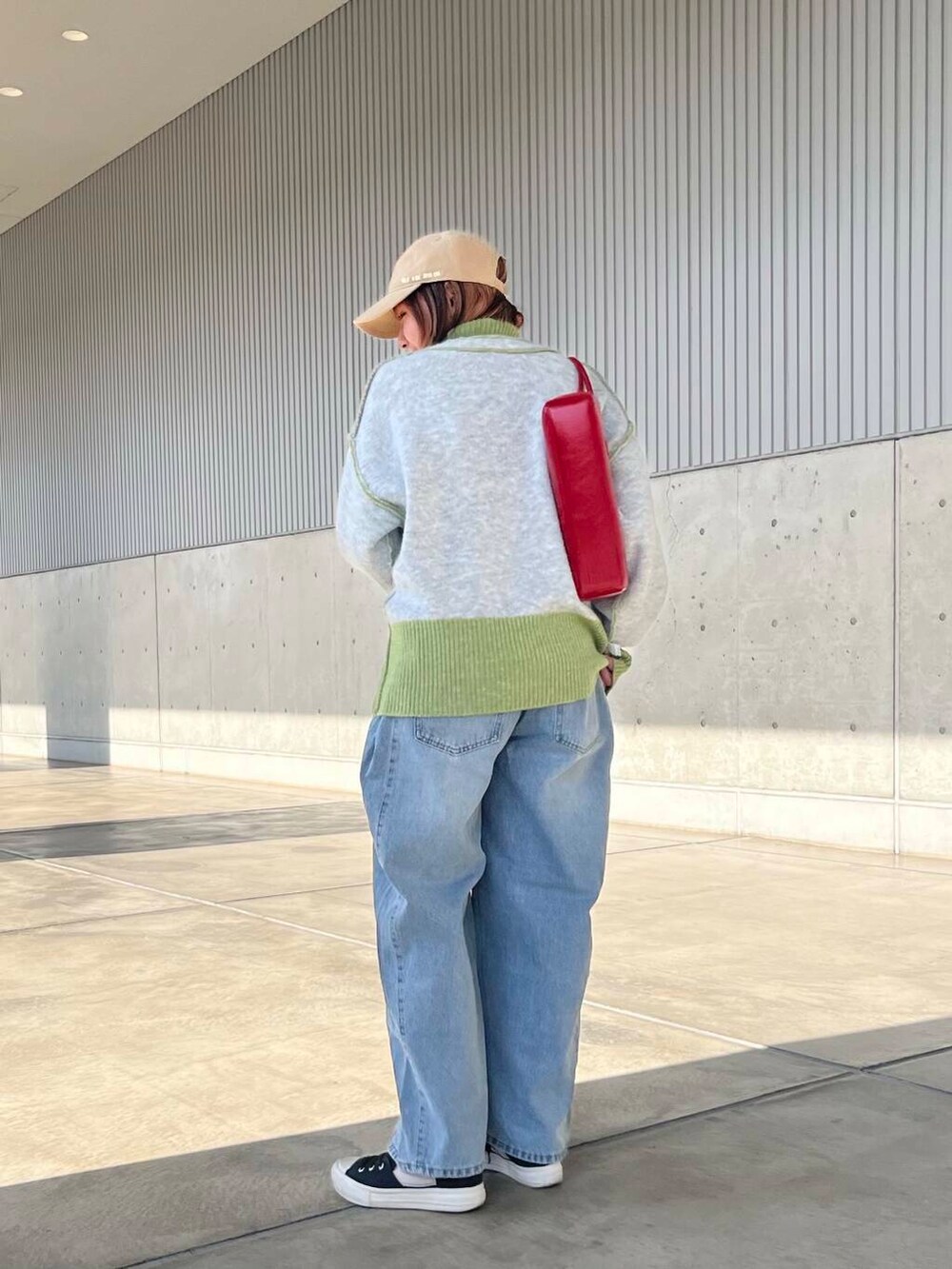 ブルー系のデニムパンツ、レッド系のショルダーバッグ、グリーン系のニット/セーターを着用したレディースの冬コーディネートの4枚目の写真