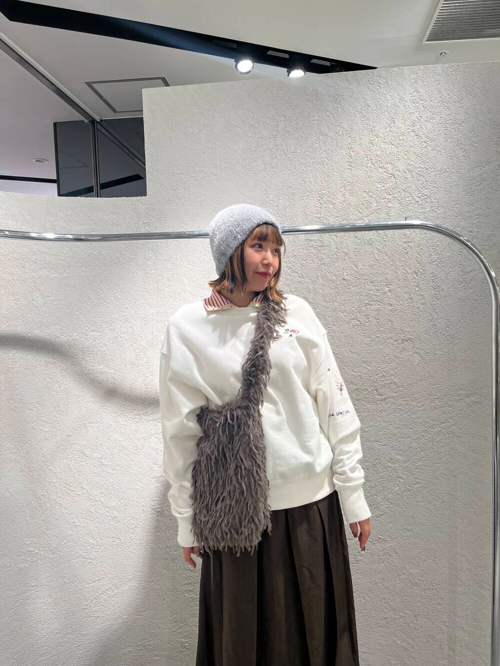 ブラウン系のショルダーバッグ、ホワイト系のスウェット、ブラウン系のワンピースを着用したレディースの冬コーディネートの4枚目の写真