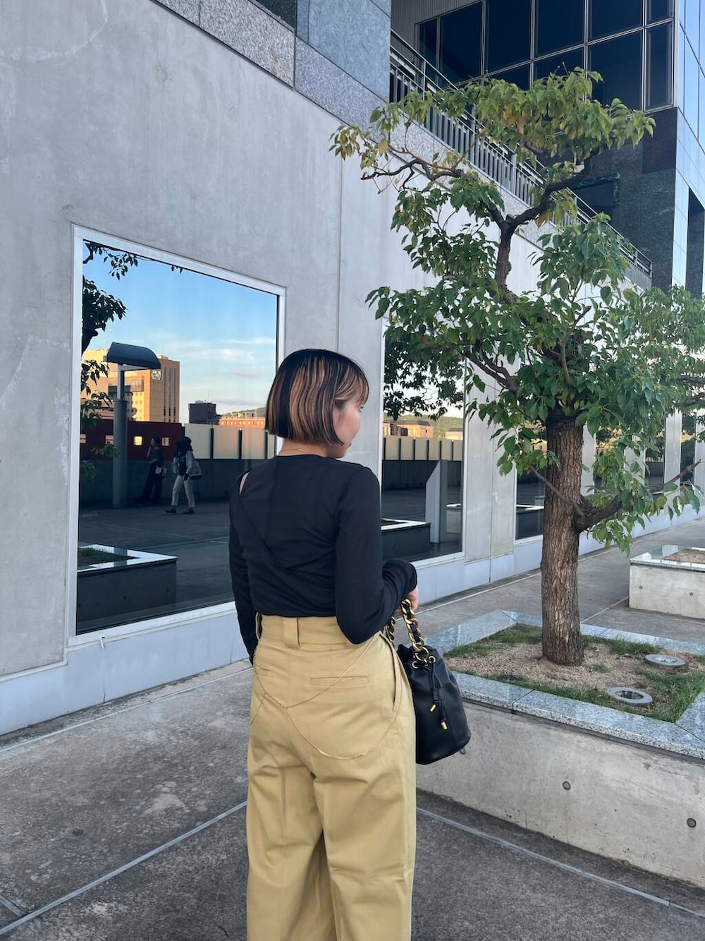 ブラック系のショルダーバッグ、ブラック系のサンダル、ベージュ系のチノパンツを着用したレディースの夏コーディネートの4枚目の写真