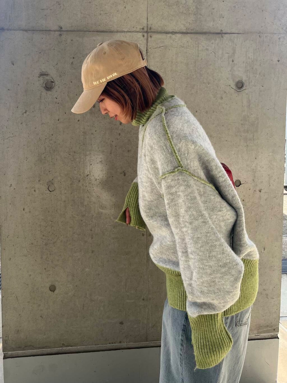 ブルー系のデニムパンツ、レッド系のショルダーバッグ、グリーン系のニット/セーターを着用したレディースの冬コーディネートの7枚目の写真