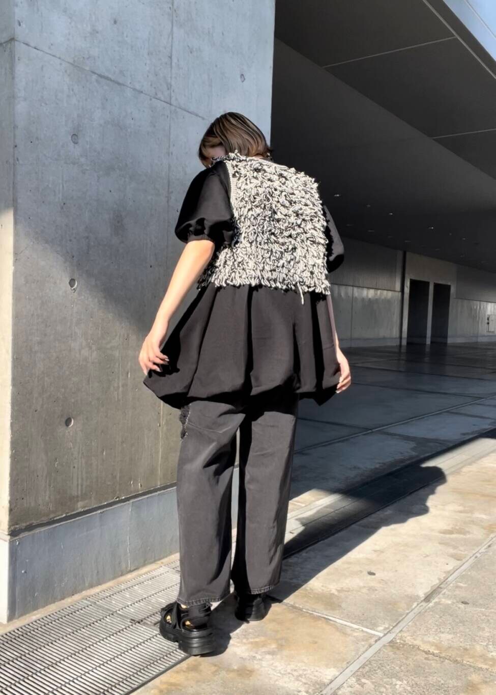 ブラック系のサンダル、ブラック系のベスト、ブラック系のデニムパンツを着用したレディースの夏コーディネートの3枚目の写真