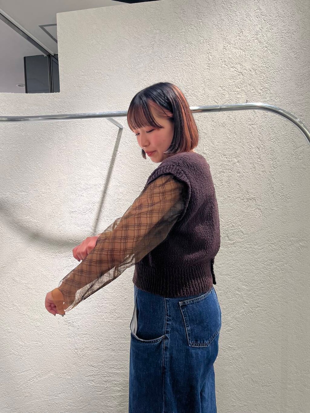 ブルー系のデニムパンツ、ブラック系のTシャツ/カットソー、ブラウン系のニット/セーターを着用したレディースの春コーディネートの6枚目の写真