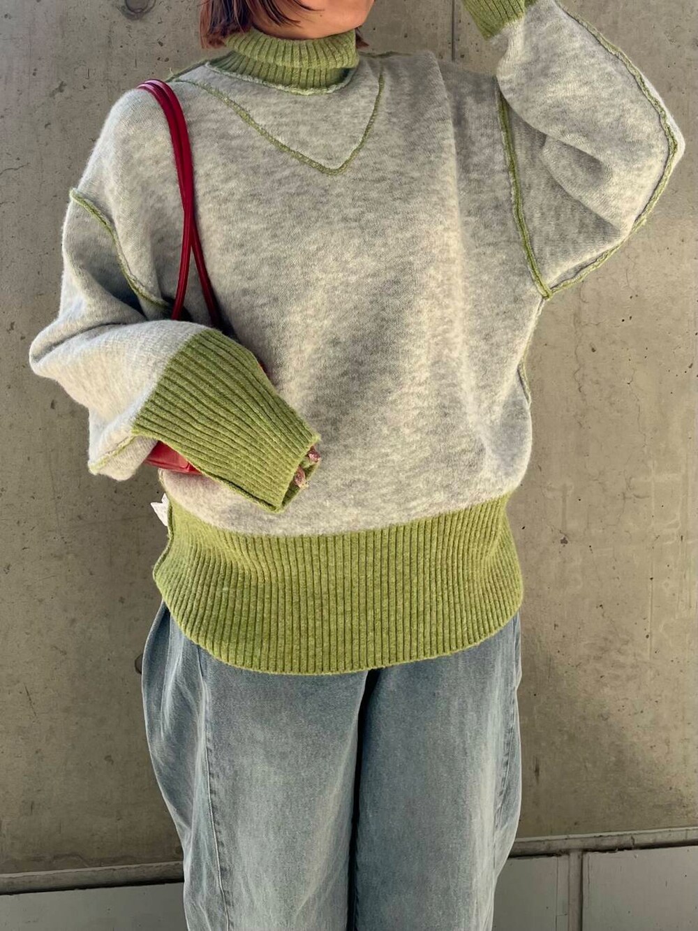 ブルー系のデニムパンツ、レッド系のショルダーバッグ、グリーン系のニット/セーターを着用したレディースの冬コーディネートの5枚目の写真