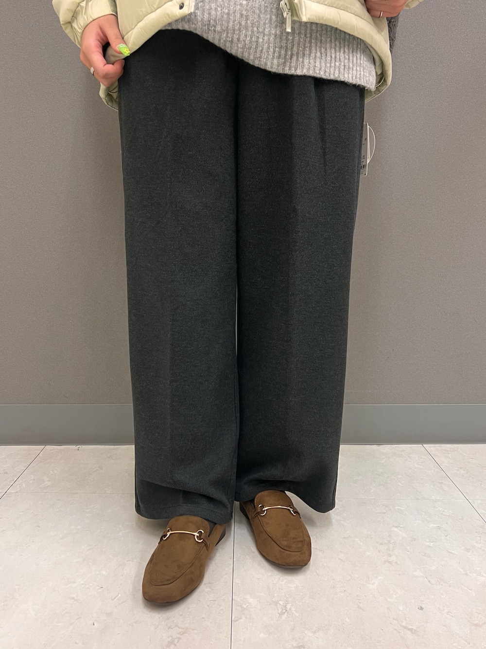 グレー系のニット/セーター、ベージュ系のダウンジャケット/コート、ベージュ系のボストンバッグを着用したレディースの秋コーディネートの3枚目の写真