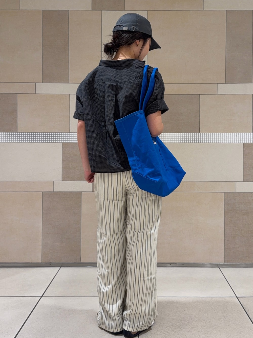ブルー系のトートバッグ、ベージュ系のその他パンツ、ブラウン系のスニーカーを着用したレディースの夏コーディネートの2枚目の写真