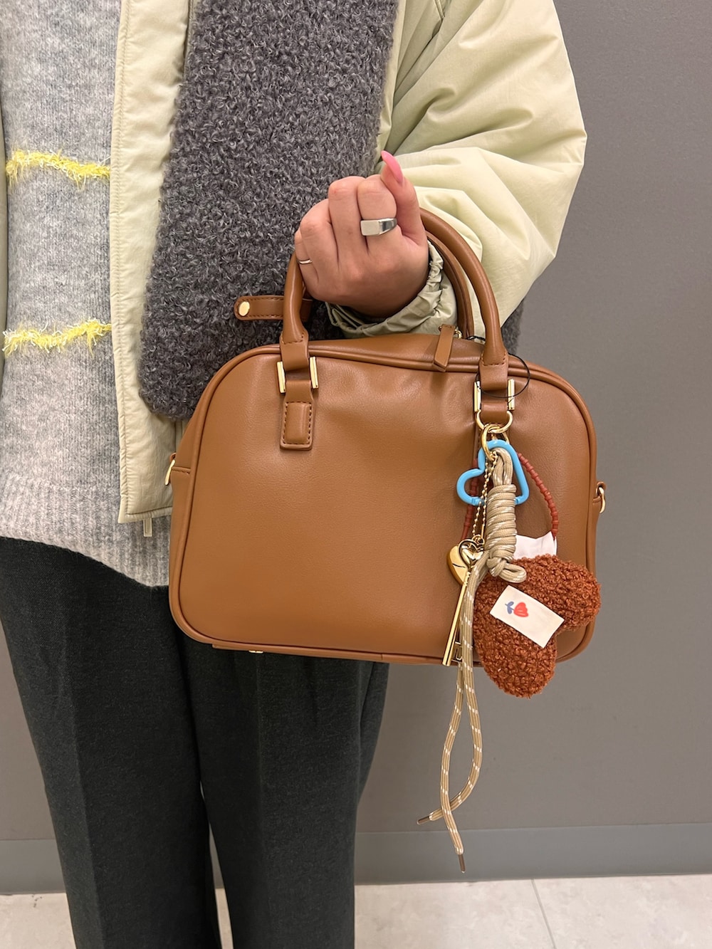 グレー系のニット/セーター、ベージュ系のダウンジャケット/コート、ベージュ系のボストンバッグを着用したレディースの秋コーディネートの5枚目の写真