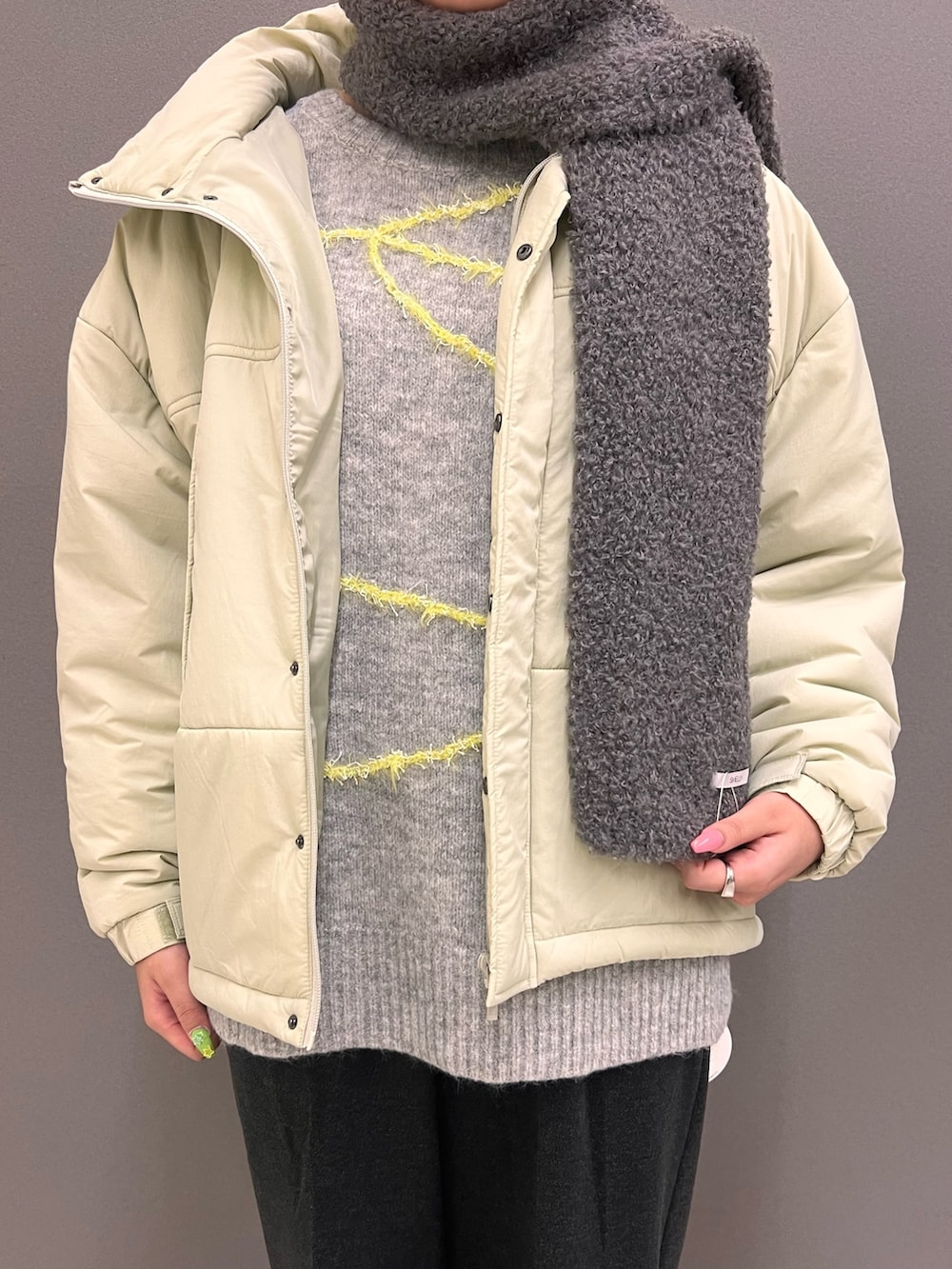 グレー系のニット/セーター、ベージュ系のダウンジャケット/コート、ベージュ系のボストンバッグを着用したレディースの秋コーディネートの2枚目の写真