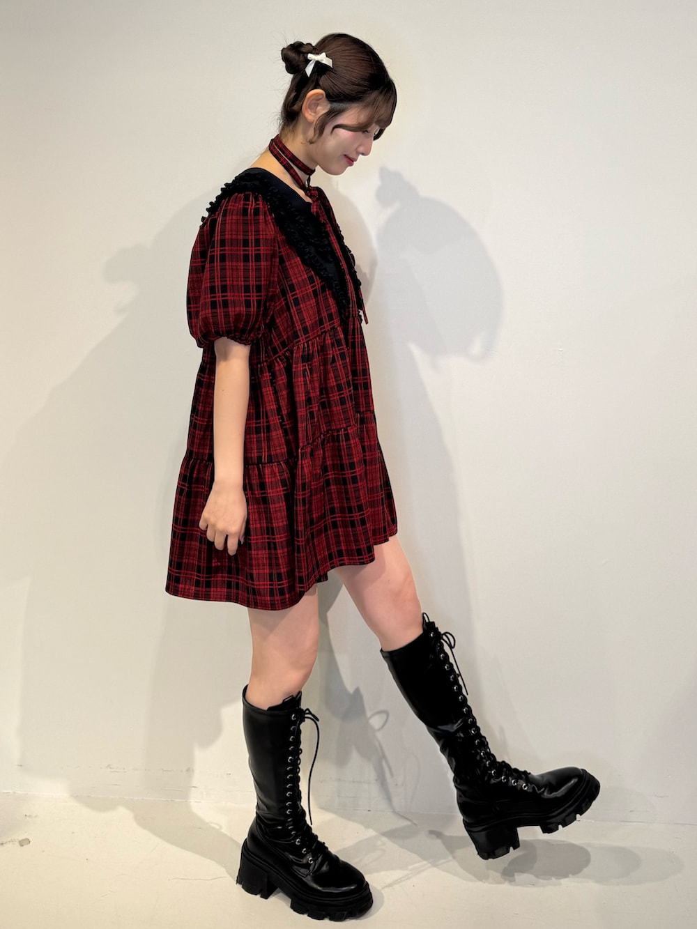 レッド系のワンピース、ブラック系のブーツを着用したレディースの冬コーディネートの3枚目の写真