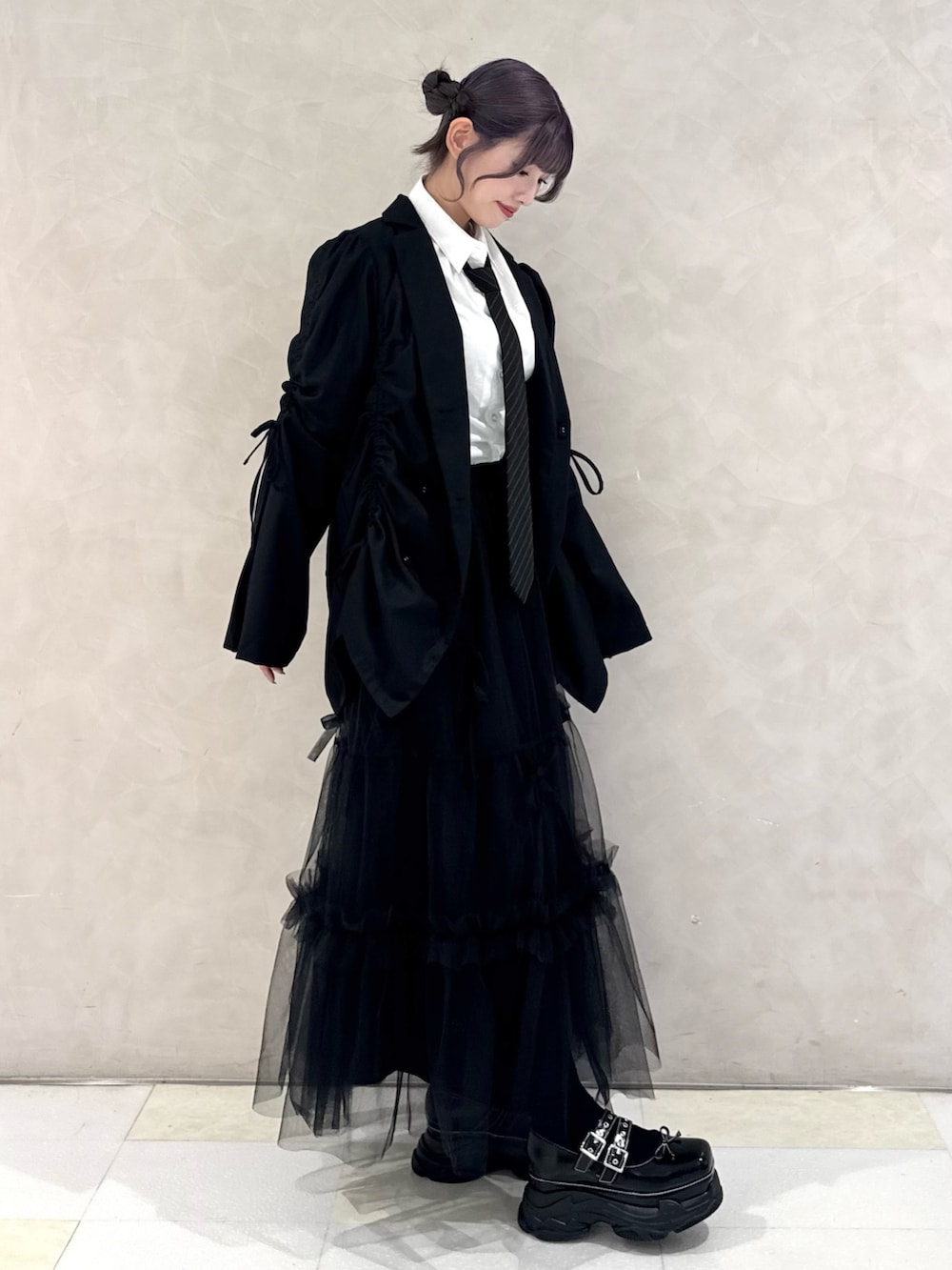 ブラック系のテーラードジャケット、ホワイト系のシャツ/ブラウス、ブラック系のネクタイを着用したレディースの秋コーディネートの2枚目の写真