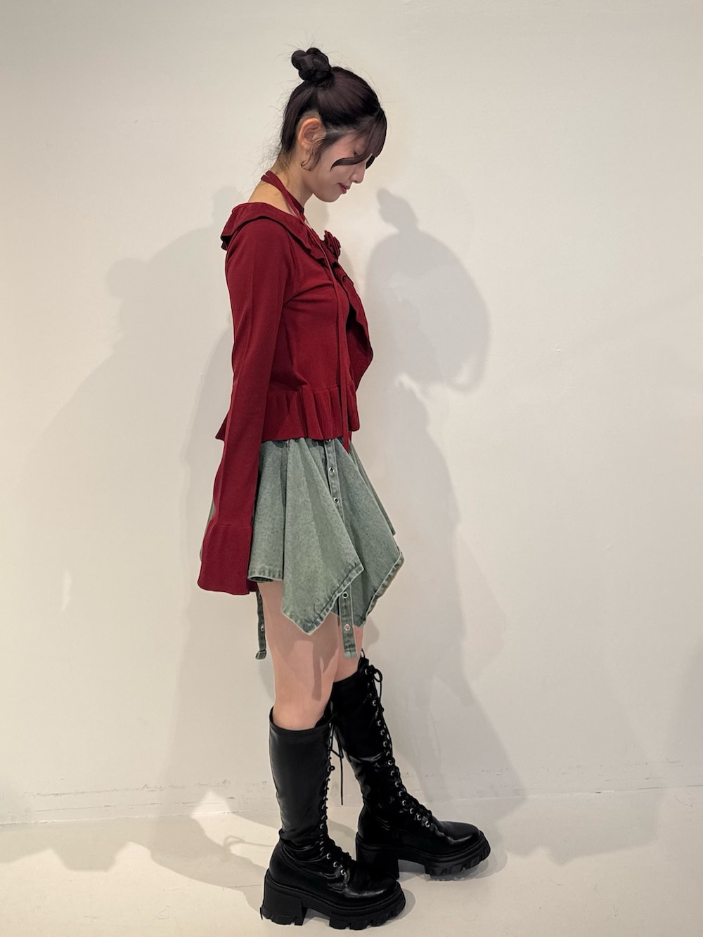 レッド系のニット/セーター、ブルー系のデニムスカート、ブラック系のブーツを着用したレディースの冬コーディネートの3枚目の写真