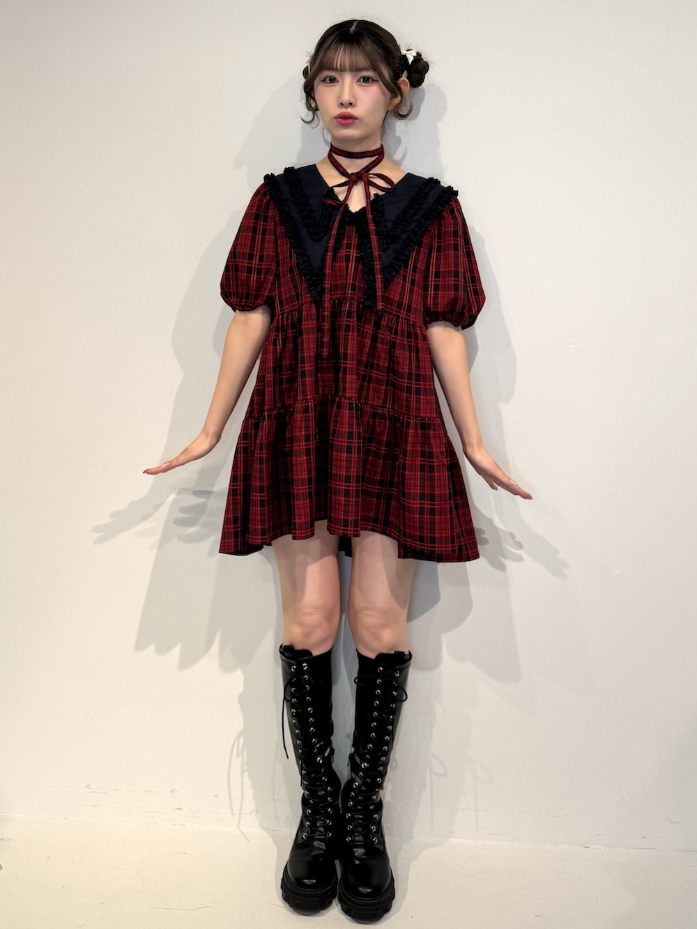 レッド系のワンピース、ブラック系のブーツを着用したレディースの冬コーディネートの2枚目の写真