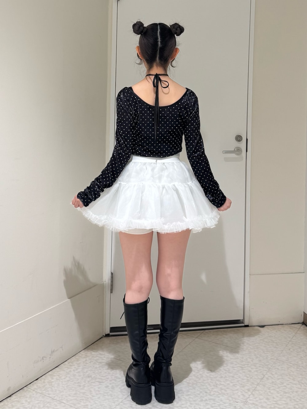 ブラック系のTシャツ/カットソー、ホワイト系のスカート、ブラック系のブーツを着用したレディースの冬コーディネートの4枚目の写真