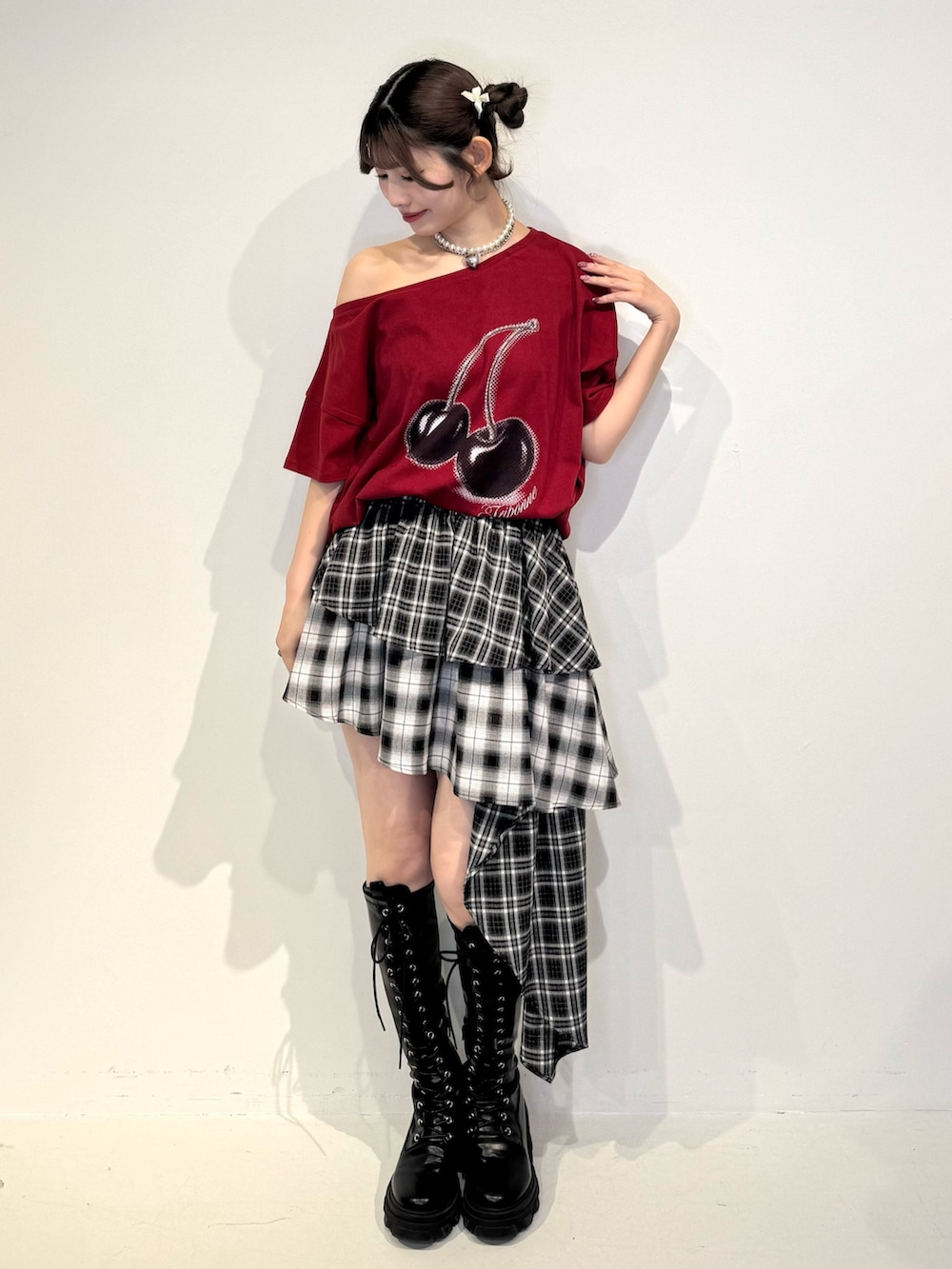 レッド系のTシャツ/カットソー、ブラック系のスカート、ブラック系のブーツを着用したレディースの春コーディネートの2枚目の写真