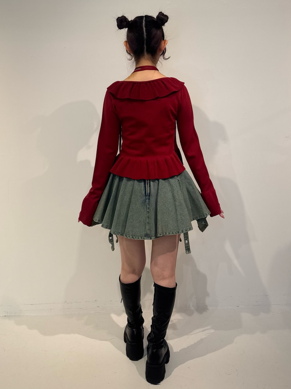 レッド系のニット/セーター、ブルー系のデニムスカート、ブラック系のブーツを着用したレディースの冬コーディネートの4枚目の写真