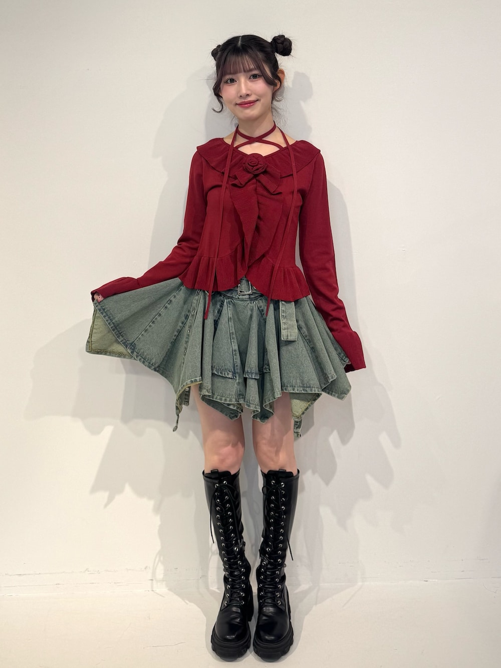 レッド系のニット/セーター、ブルー系のデニムスカート、ブラック系のブーツを着用したレディースの冬コーディネートの2枚目の写真