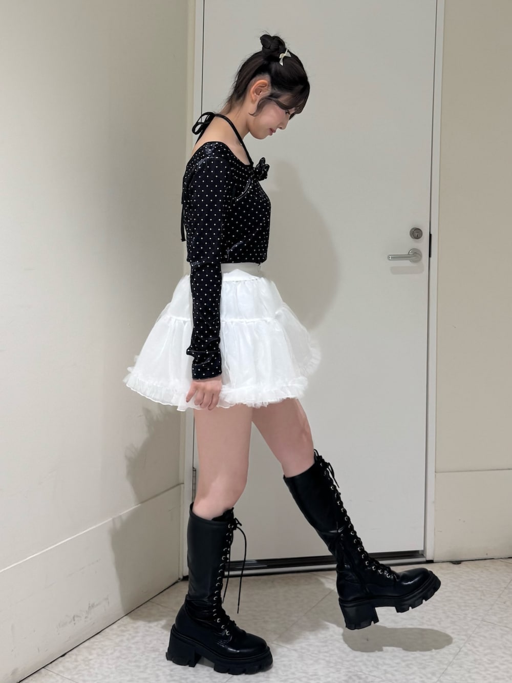 ブラック系のTシャツ/カットソー、ホワイト系のスカート、ブラック系のブーツを着用したレディースの冬コーディネートの3枚目の写真