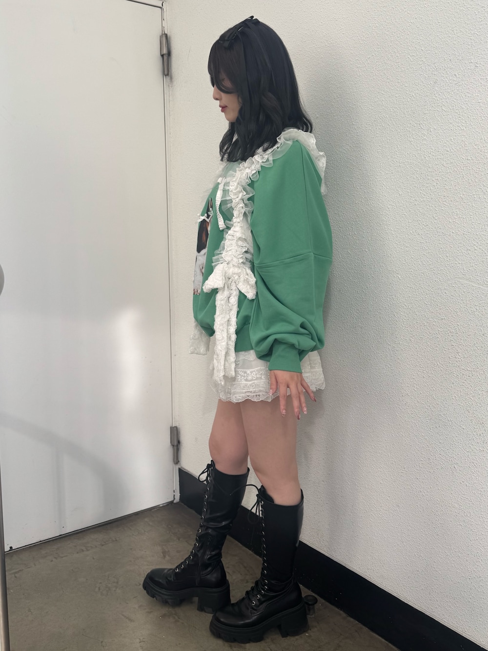 グリーン系のスウェット、ブラック系のブーツ、ホワイト系のベルトを着用したレディースの冬コーディネートの3枚目の写真