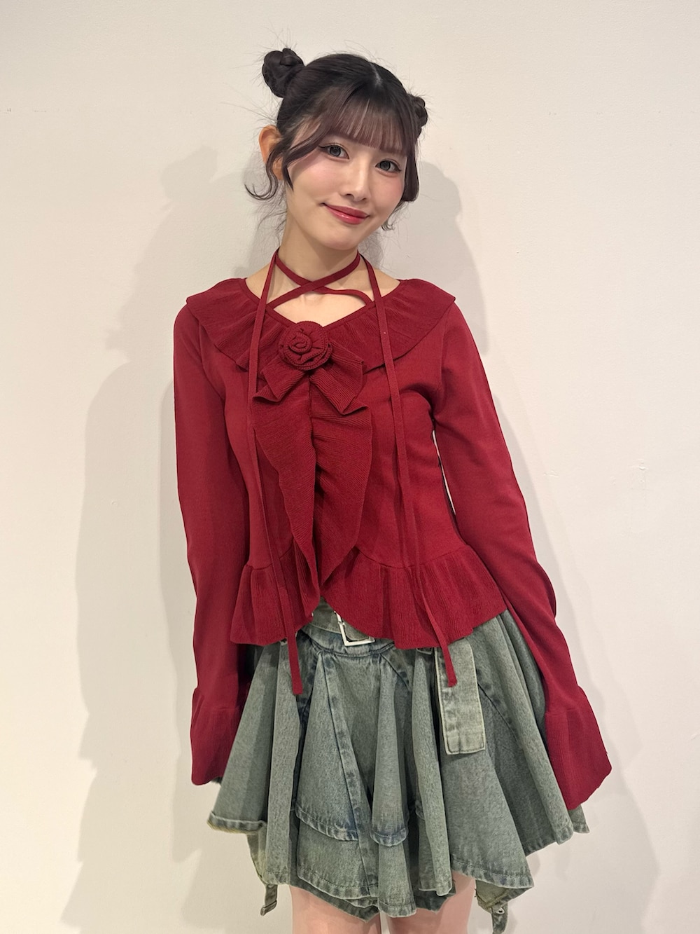 レッド系のニット/セーター、ブルー系のデニムスカート、ブラック系のブーツを着用したレディースの冬コーディネートの6枚目の写真