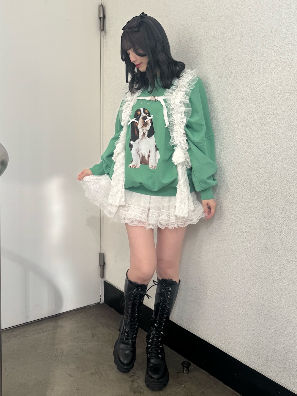 グリーン系のスウェット、ブラック系のブーツ、ホワイト系のベルトを着用したレディースの冬コーディネートの2枚目の写真